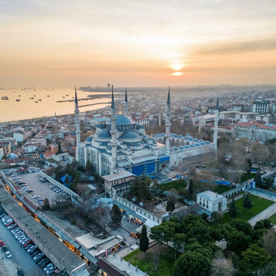 Aerial drone view of Istanbul at sunset, Turkey. The Blue Mosque, with gardens and buildings around, Bosporus strait with ships